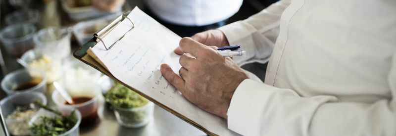 Une personne écrivant sur un clipboard tout en observant un processus alimentaire